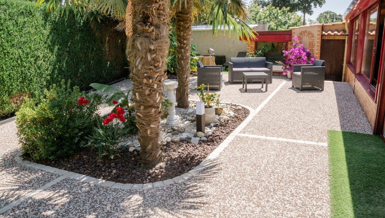 Jardin paysager avec terrasse en béton désactivé, massifs fleuris et palmiers, aménagé par Artisans de France
